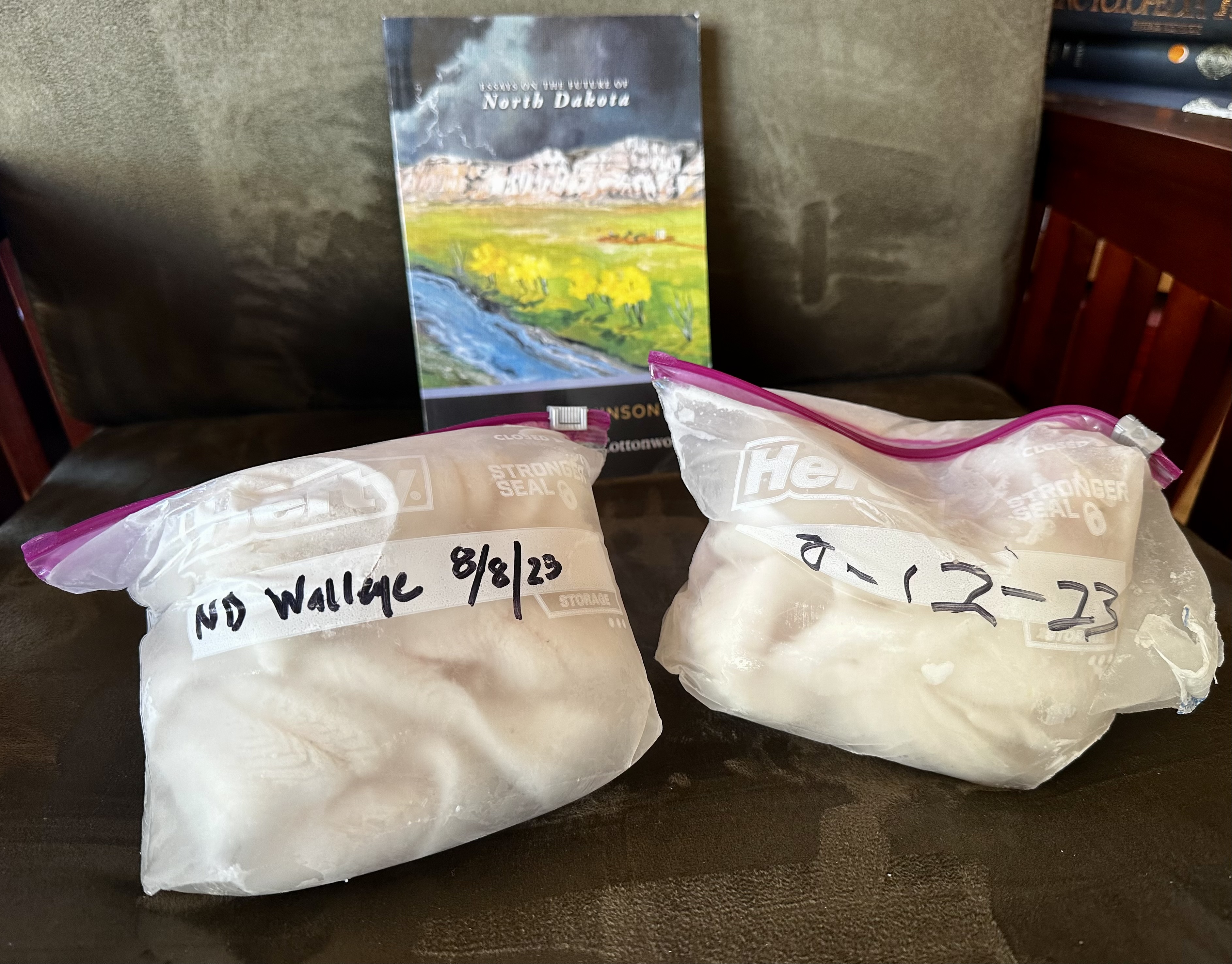 Carl gifts Clay to Ziplock bags of frozen walleye, pictured here with a copy of Clay's book on North Dakota, The Language of the Cottonwoods.