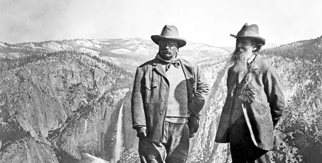 Theodore Roosevelt and John Muir stand at Glacier Point, Yosemite National Park, during their 1903 visit, with Yosemite Falls in the background. (Library of Congress)