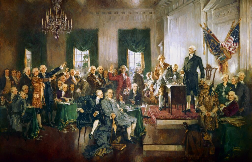 A artist rendition of the signing of the United States Constitution with George Washington, Benjamin Franklin, and Alexander Hamilton (left to right in the foreground).